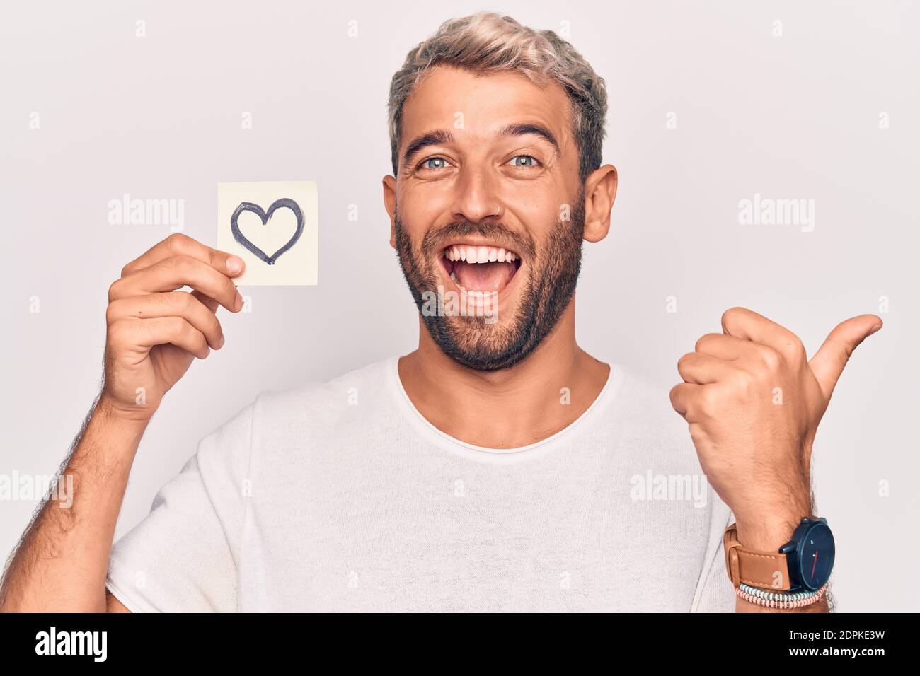 Handsome Blond Man With Beard Holding Reminder With Heart Shape Over White Background Pointing 6877