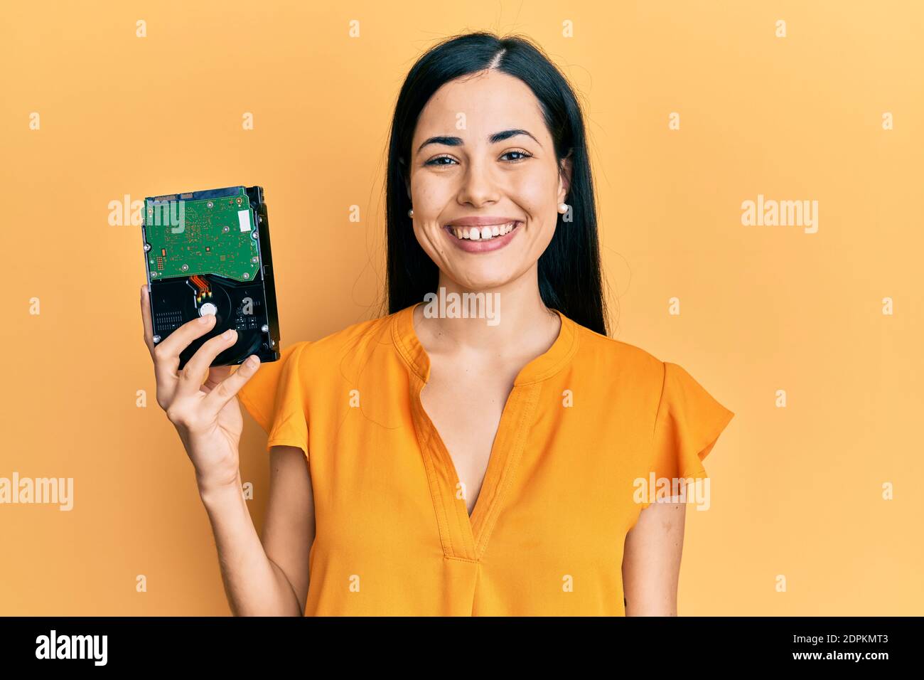 Beautiful young woman holding hard disk looking positive and happy ...