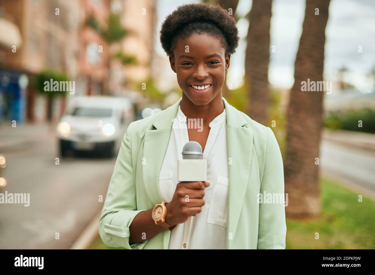 Young african american reporter woman using microphone at the city ...