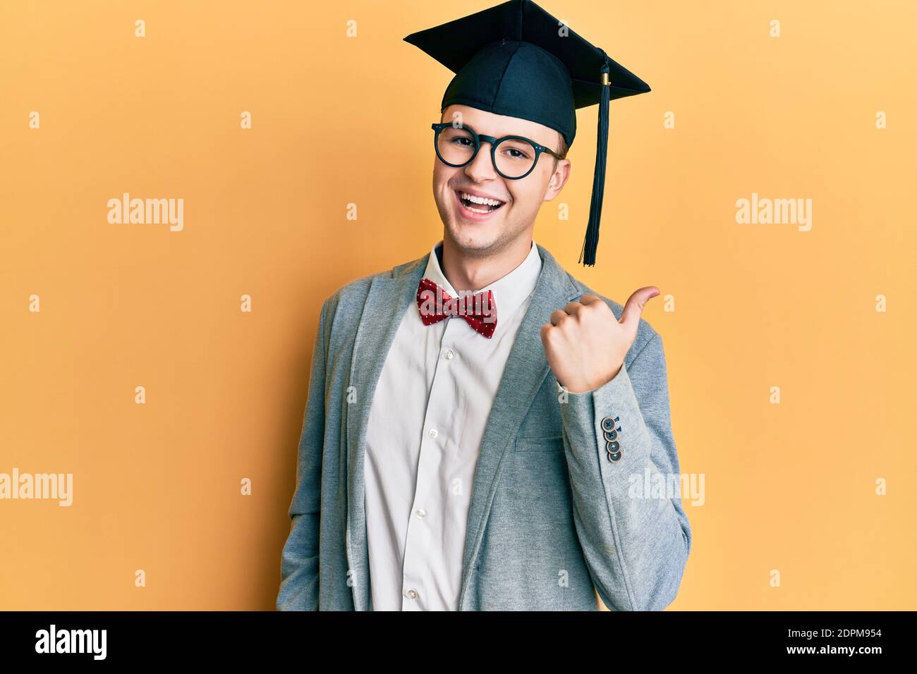 Young caucasian nerd man wearing glasses and graduation cap pointing ...