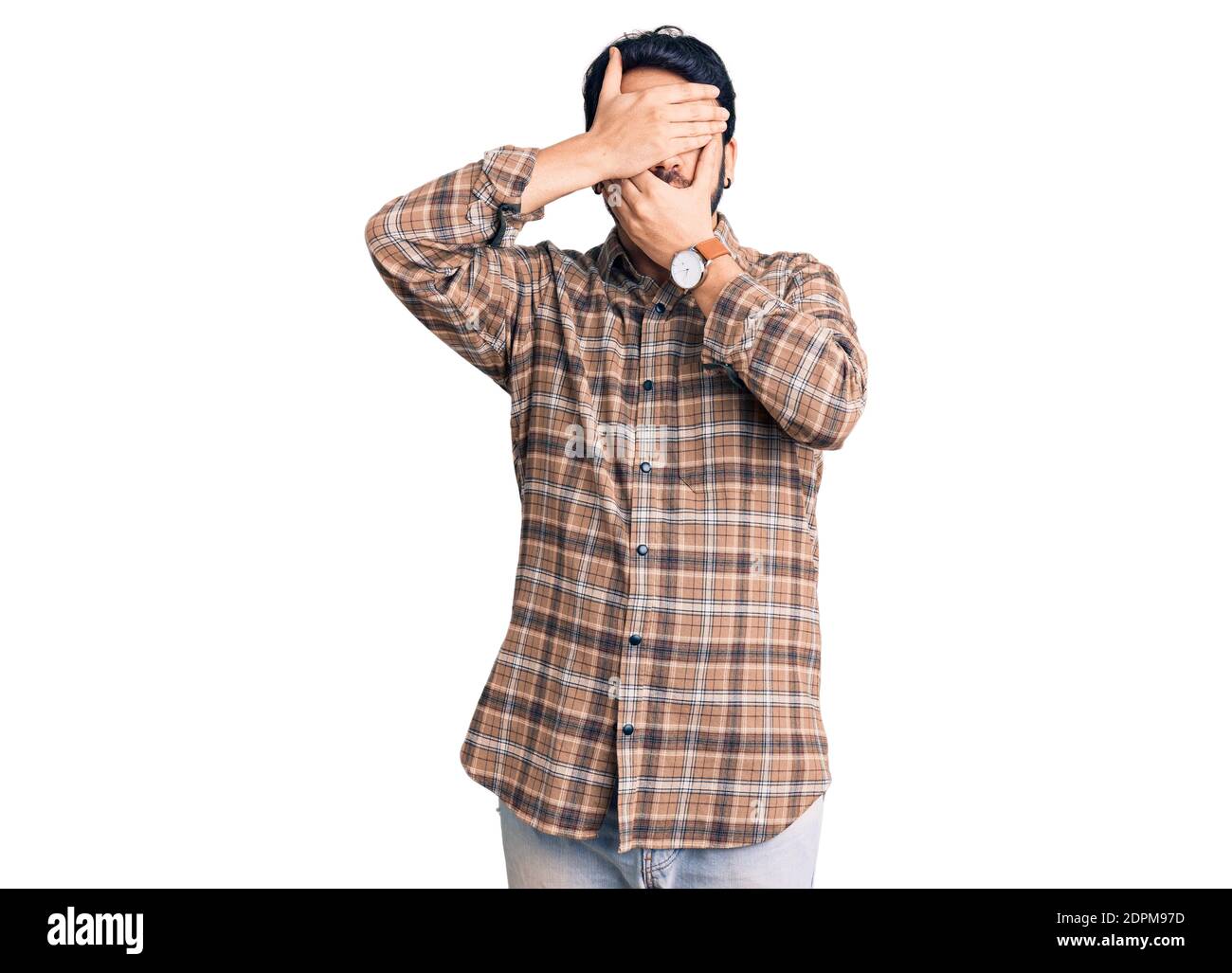 Young hispanic man wearing casual clothes covering eyes and mouth with ...