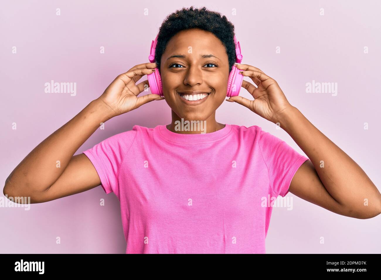 Young african american girl listening to music using headphones smiling ...