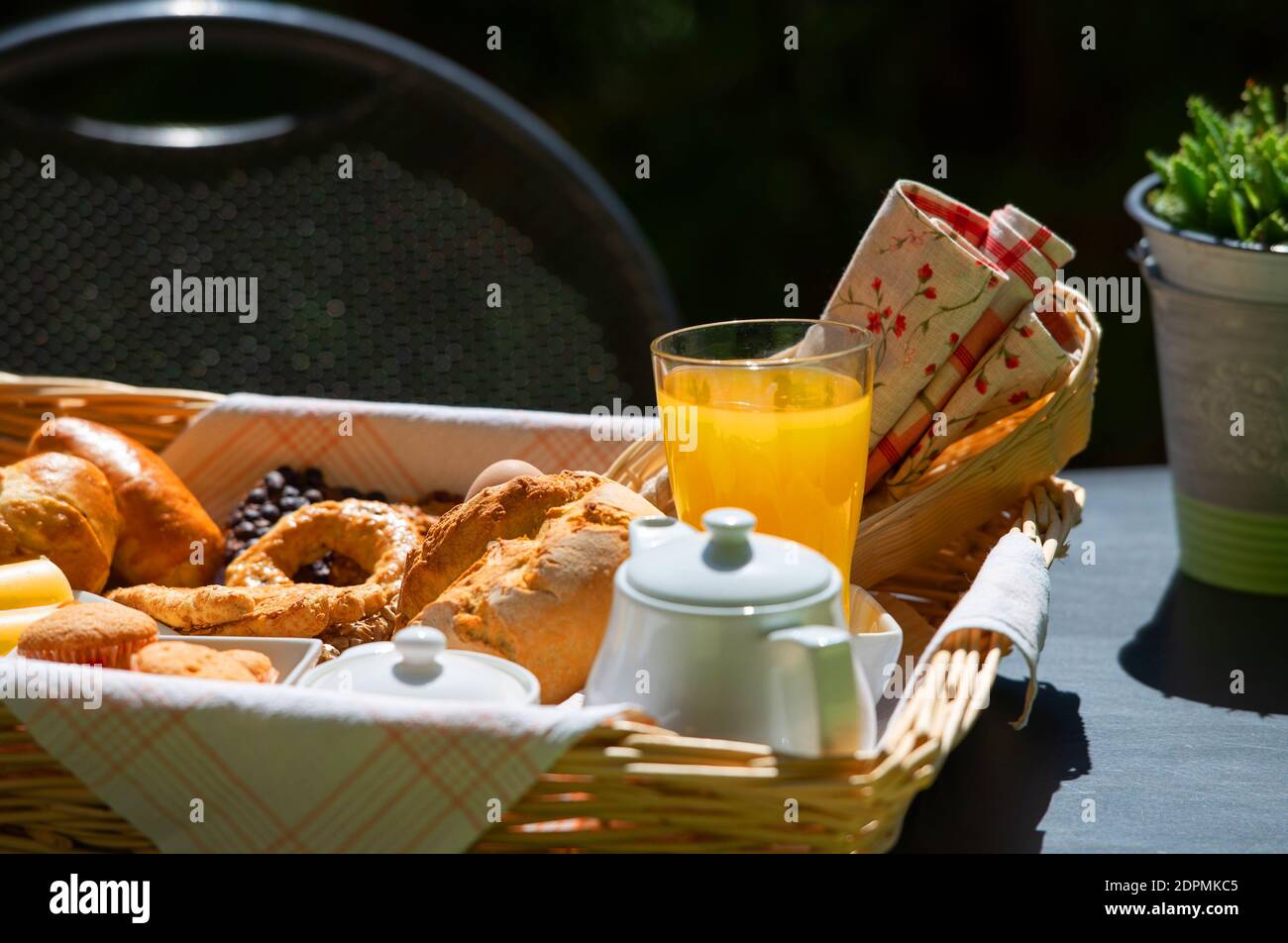 Close Up of continental breakfast with orange juice, tea and fresh croissants on table top surface in summer garden background Stock Photo