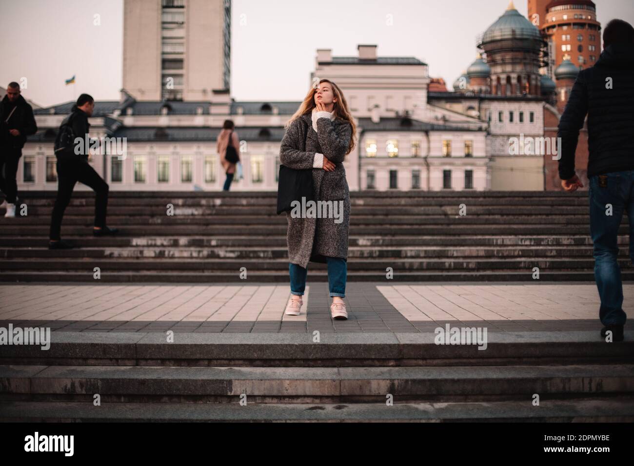 Thoughtful young woman walking in city in autumn Stock Photo