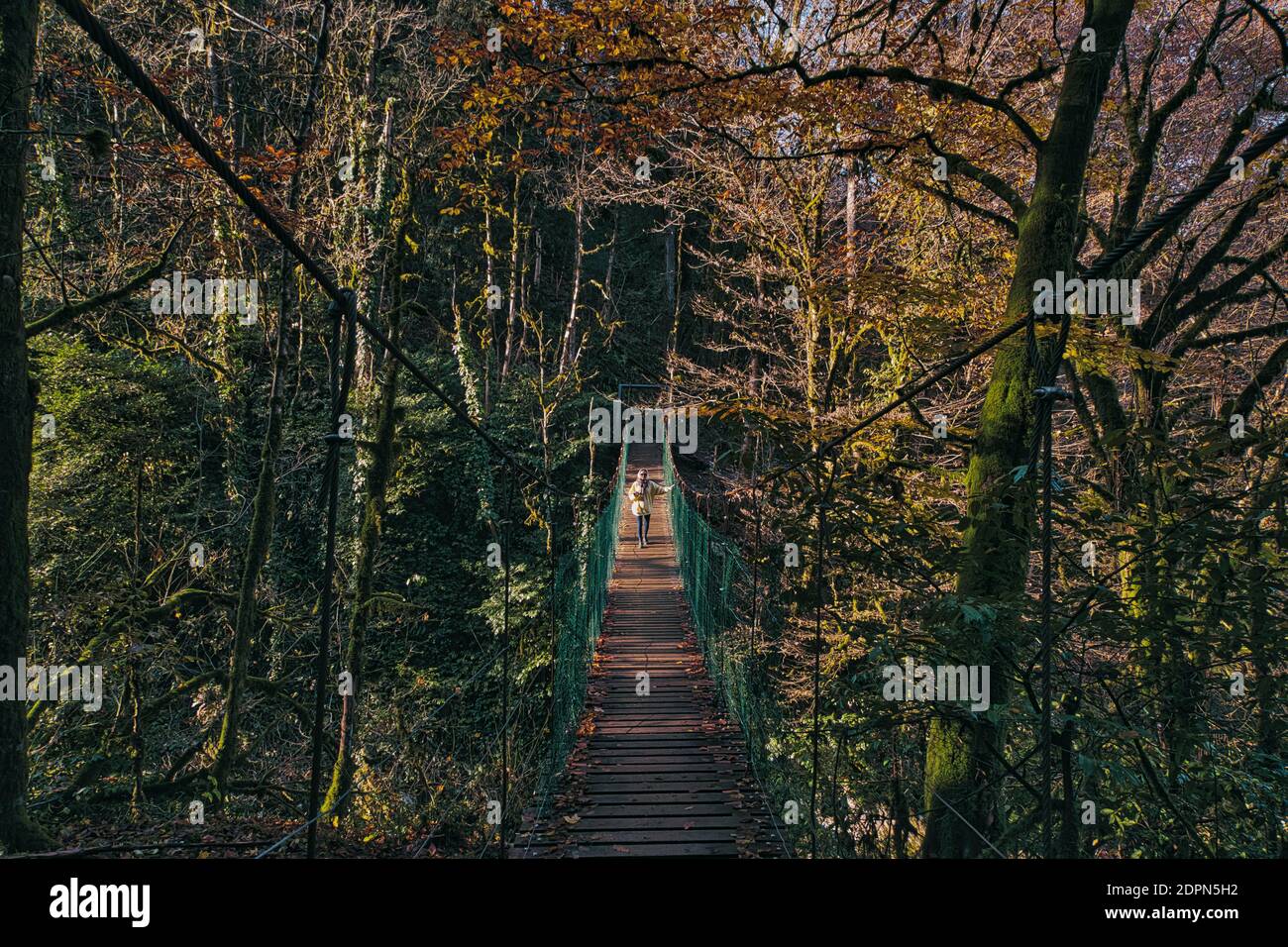 Young woman crossing suspension bridge Stock Photo - Alamy