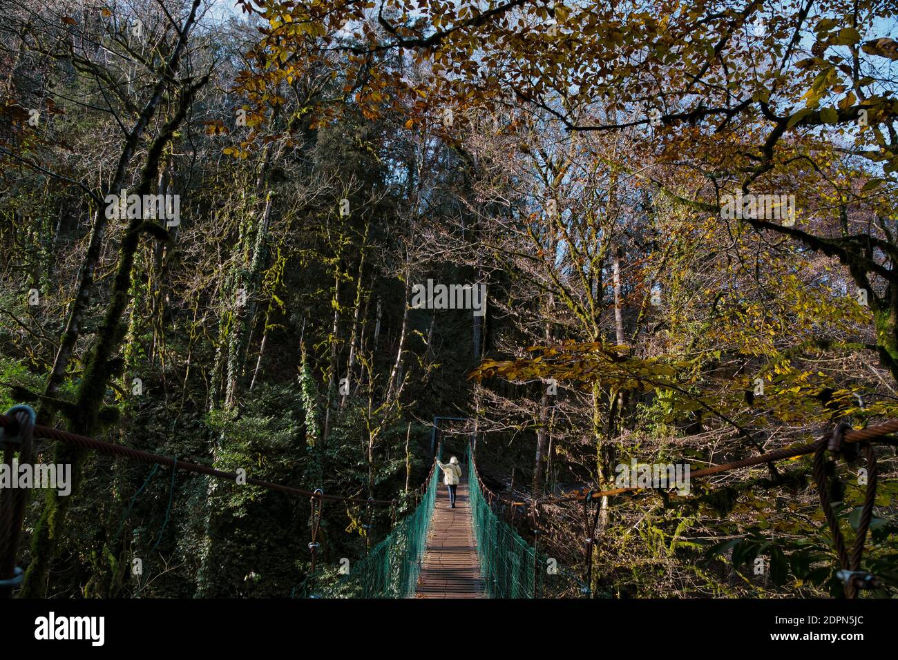 Young woman crossing suspension bridge Stock Photo - Alamy
