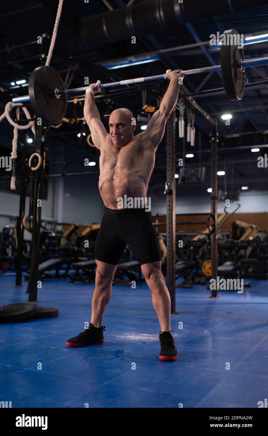 Full body powerful senior sportsman lifting barbell over head during  functional workout in modern gym Stock Photo - Alamy