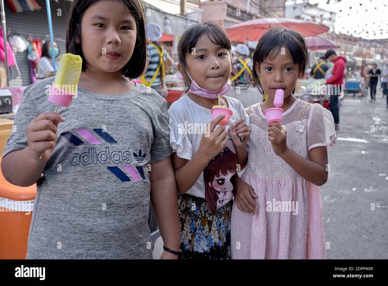 Children eating ice lollies outdoor. 3 young friends. Stock Photo