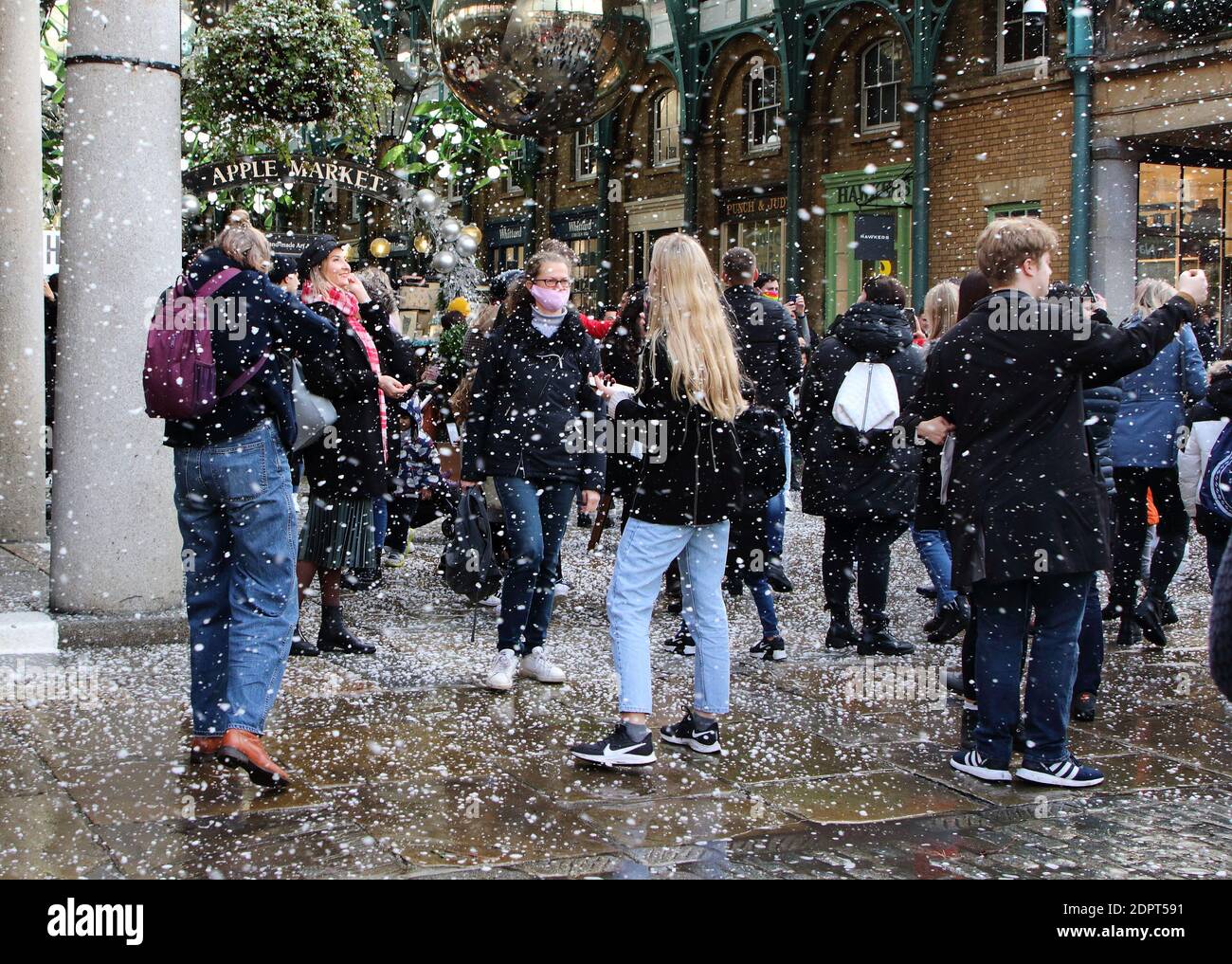 People walk through the market as the fake snow fallsPeople enjoy the