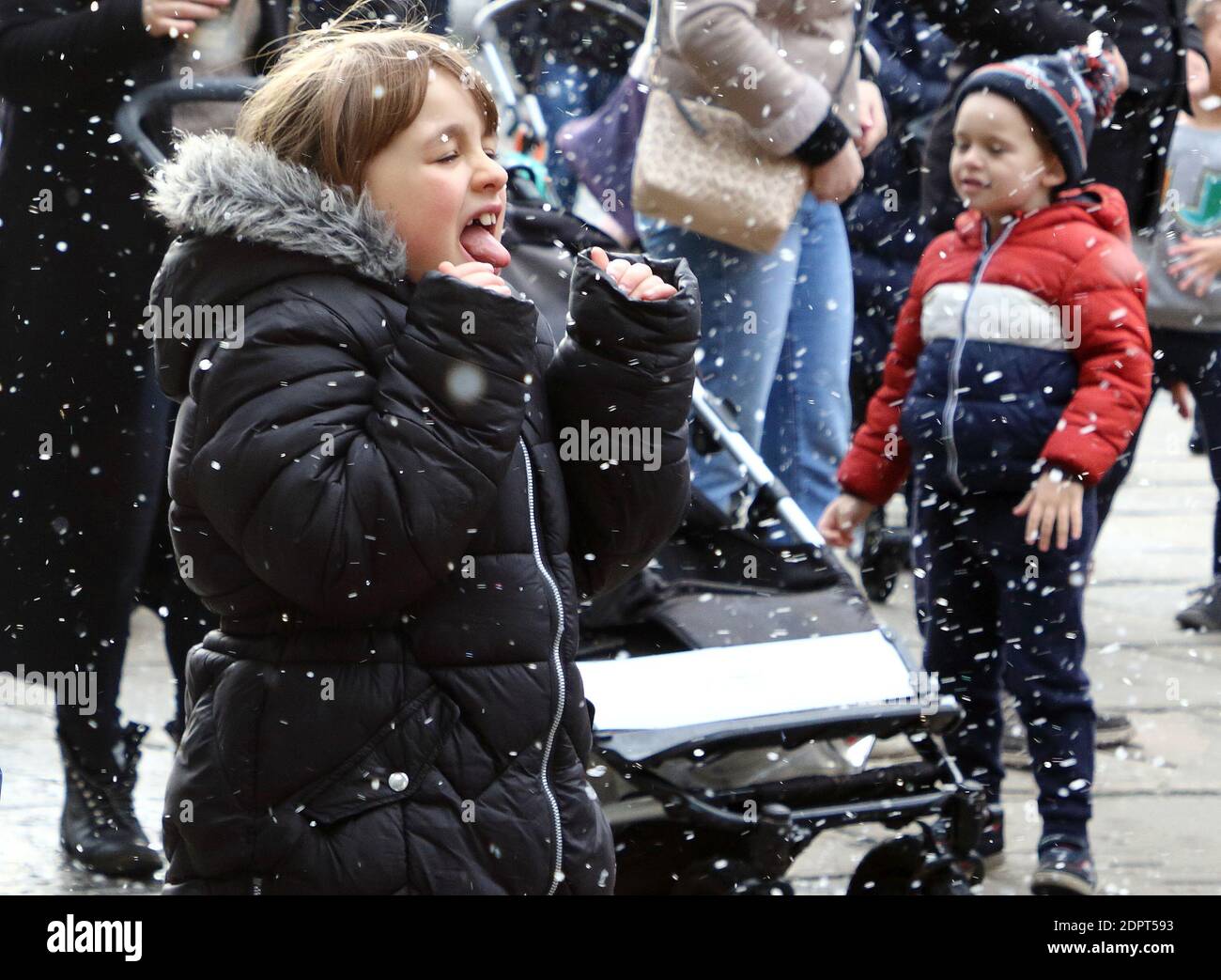 A girl looks excited to see the fake snow falling around herPeople