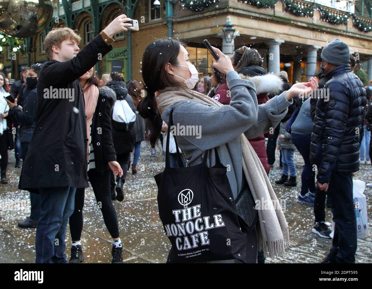 People take pictures with fake snow falling People enjoy the artificial