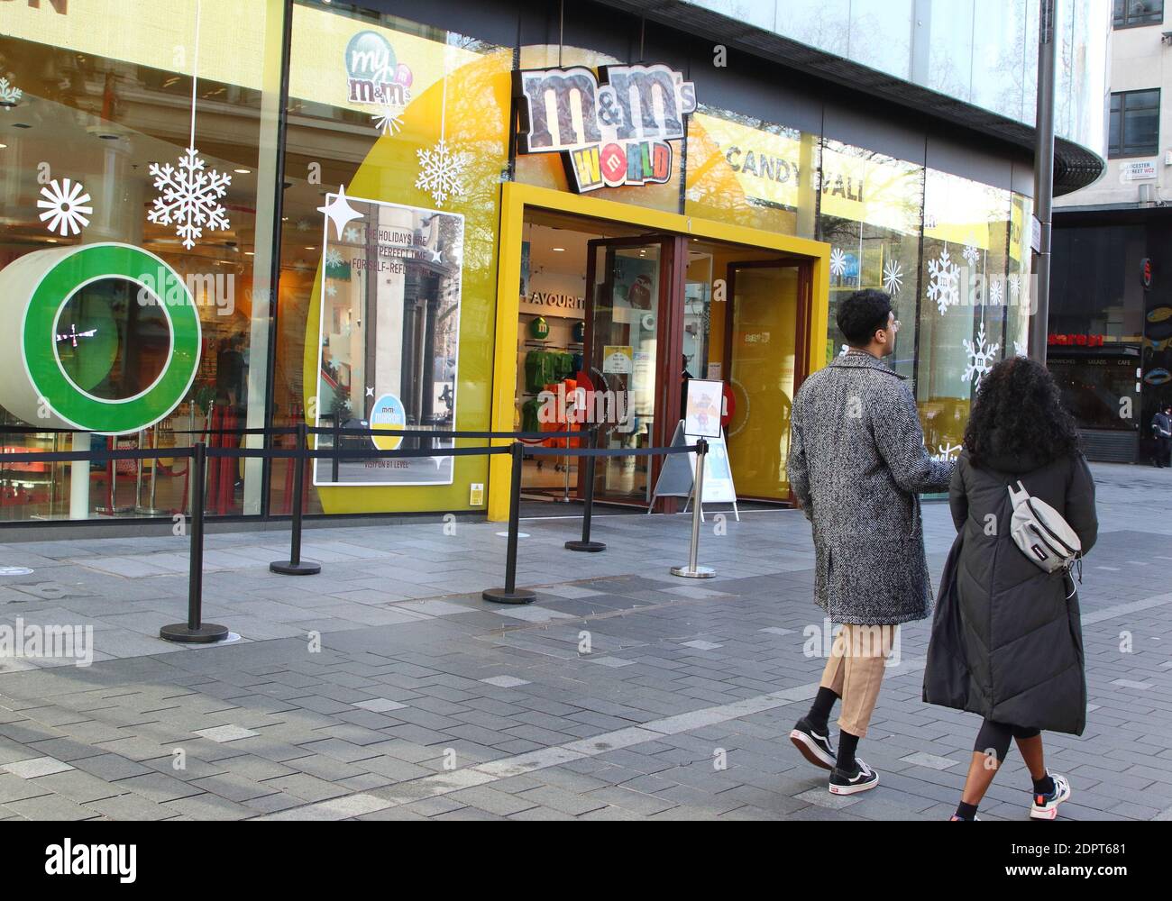 A couple walks past M&M megastore.London enters Tier 4 severe restrictions as new Mutant Covid-19 strain is found. The new variant of the virus has been found to be 70% more infectious and is currently rampant throughout London and the South East of England. Stock Photo