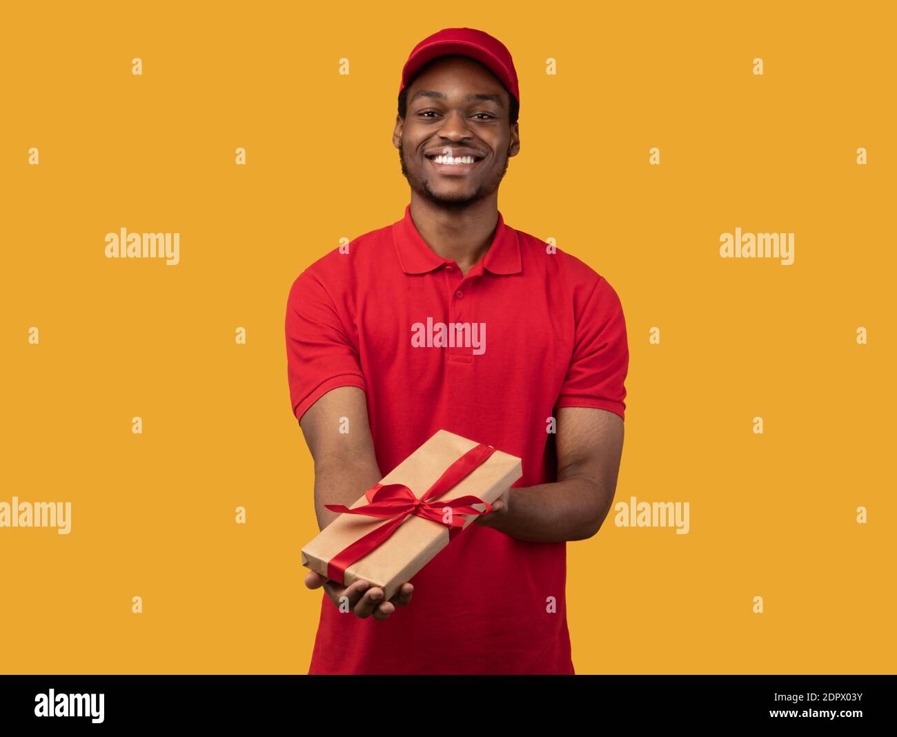 Black delivery man holding gift box showing it to camera Stock Photo