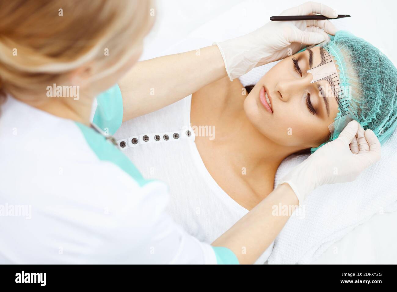 Professional beautician is going to correct eyebrow line at woman face ...