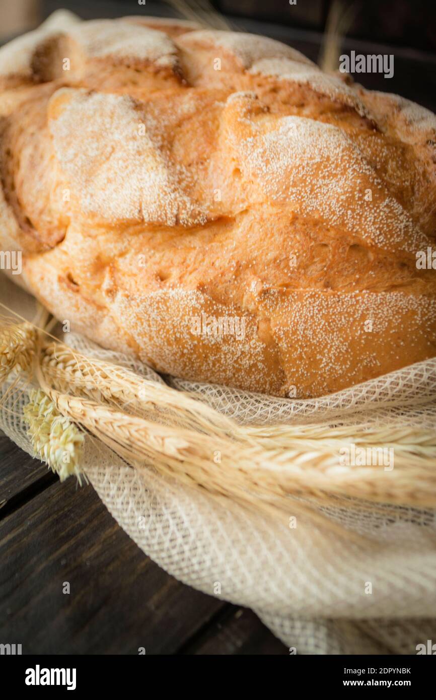 Freshly baked multi grain bread on rustic dark wooden background. Low key still life with directional natural lighting, vertical image Stock Photo
