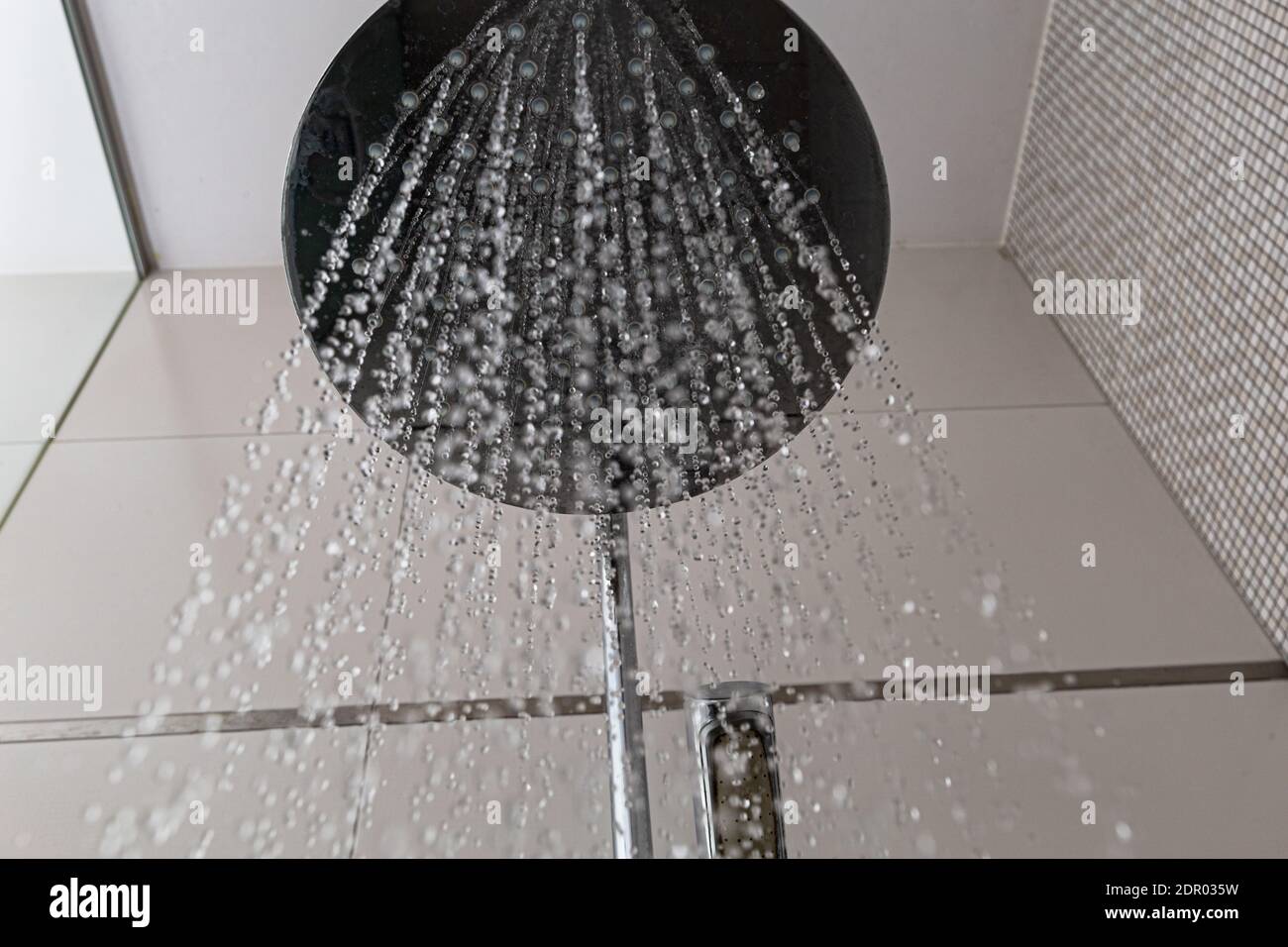 Bottom view of the rain shower head with flowing water. Stand in the