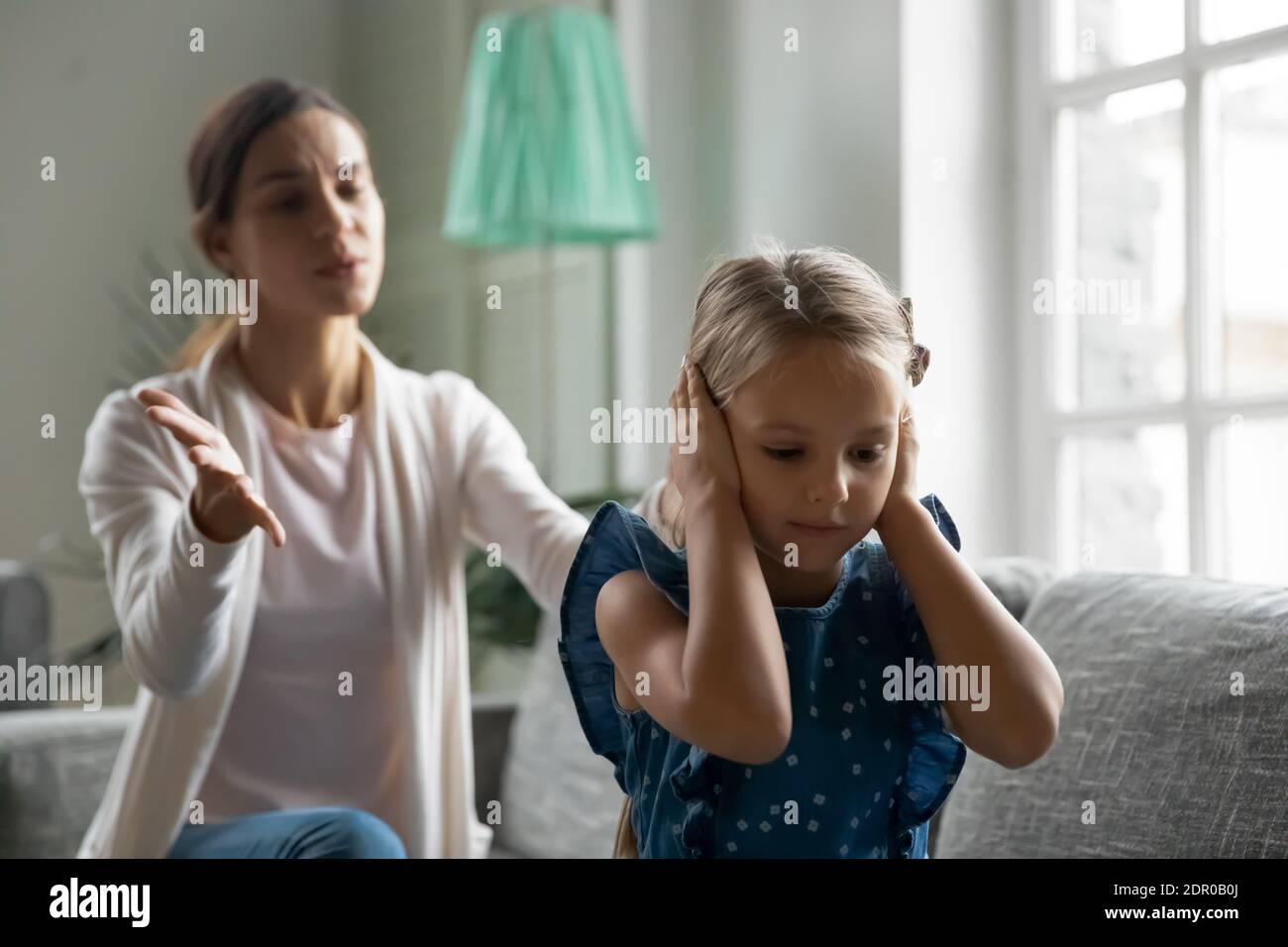 Close up upset little girl covering ears, ignoring angry yelling mother Stock Photo
