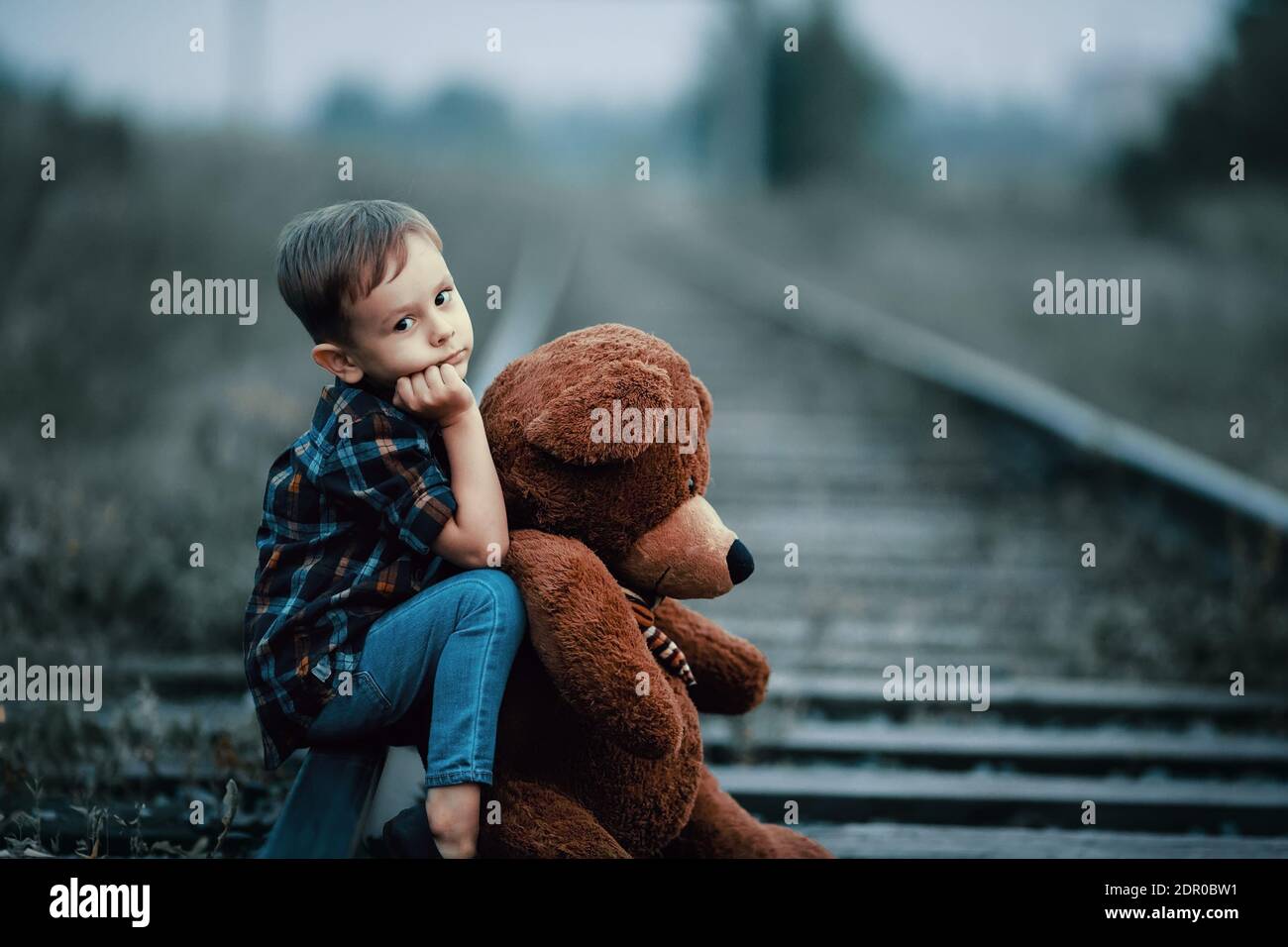 Boy With Teddy Bear Sitting On Railroad Track Stock Photo - Alamy