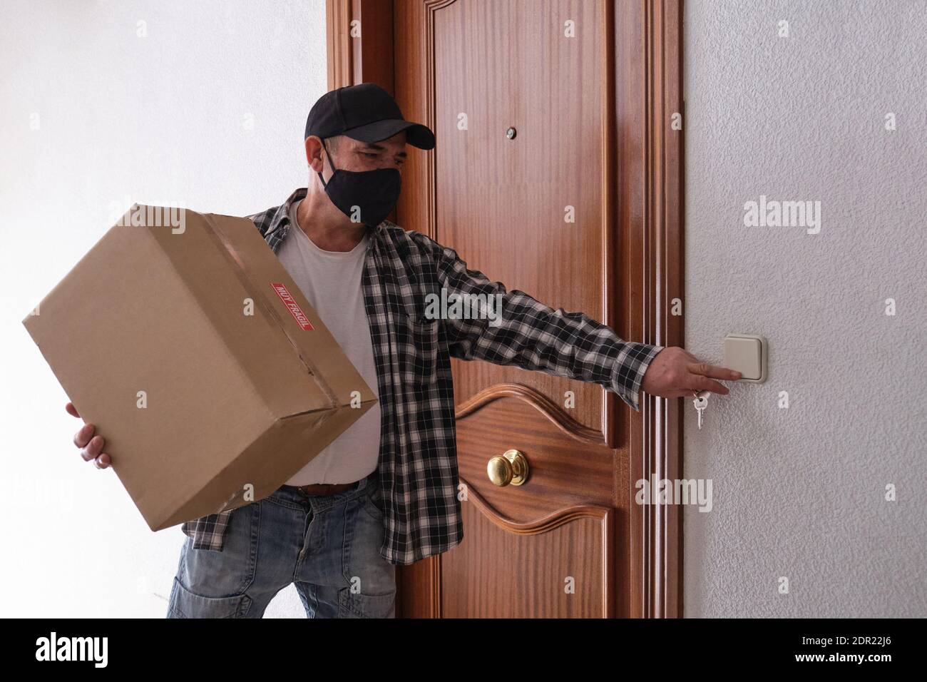 Delivery Man With Parcel Box Ringing Door Bell Stock Photo Alamy