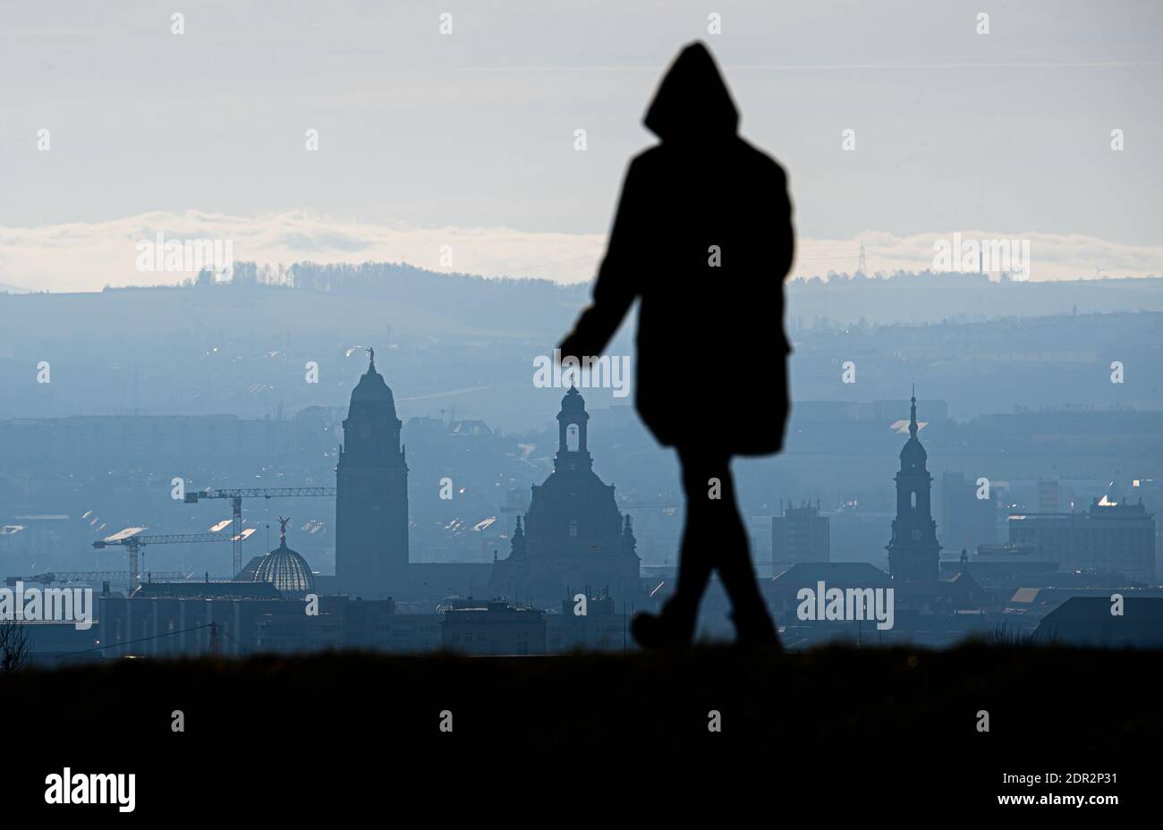 Dresden, Germany. 20th Dec, 2020. A woman walks in the New Town on a hill overlooking the Old Town in front of the City Hall (l-r), the Frauenkirche and the Kreuzkirche. A hard lockdown has come into effect in Germany to contain the Corona pandemic. Credit: Robert Michael/dpa-Zentralbild/dpa/Alamy Live News Stock Photo