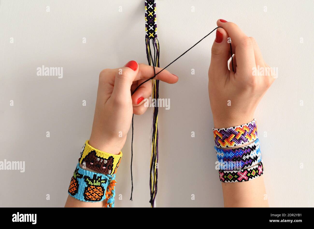 Process of weaving knot for DIY friendship bracelet. Female hands with many handmade  bracelets on wrists. step by step Stock Photo - Alamy