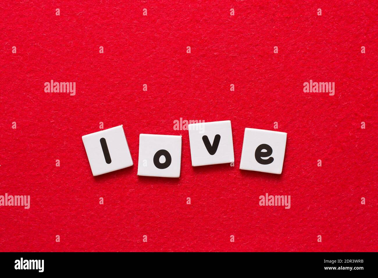 Love lettering word written by black printed letters on white sheets of paper on red background Stock Photo