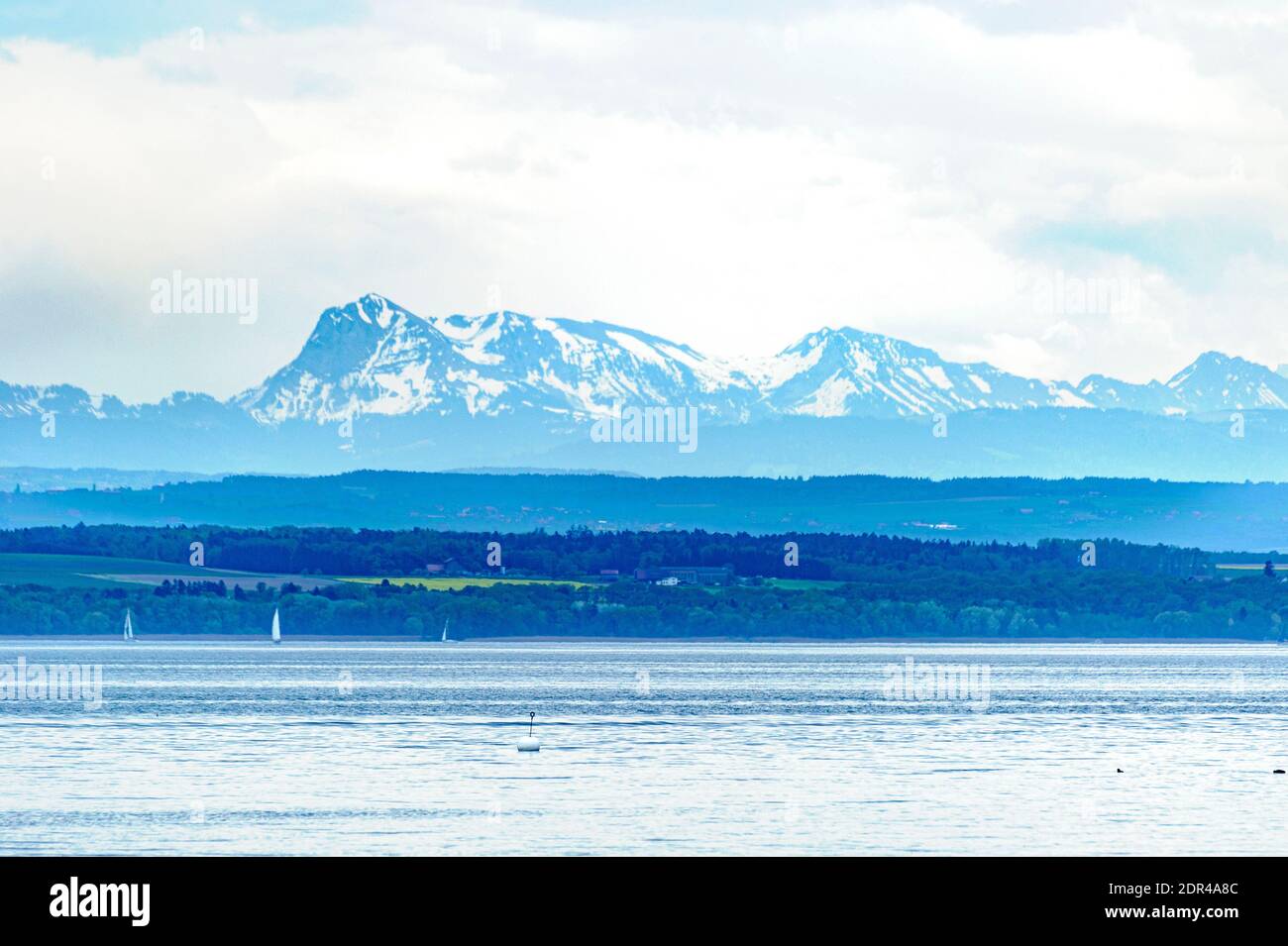 View of Lake Neuchâtel at blue time. In the background, view of the highest peaks of the Swiss Alps.  Different points of the landscape are spread out Stock Photo