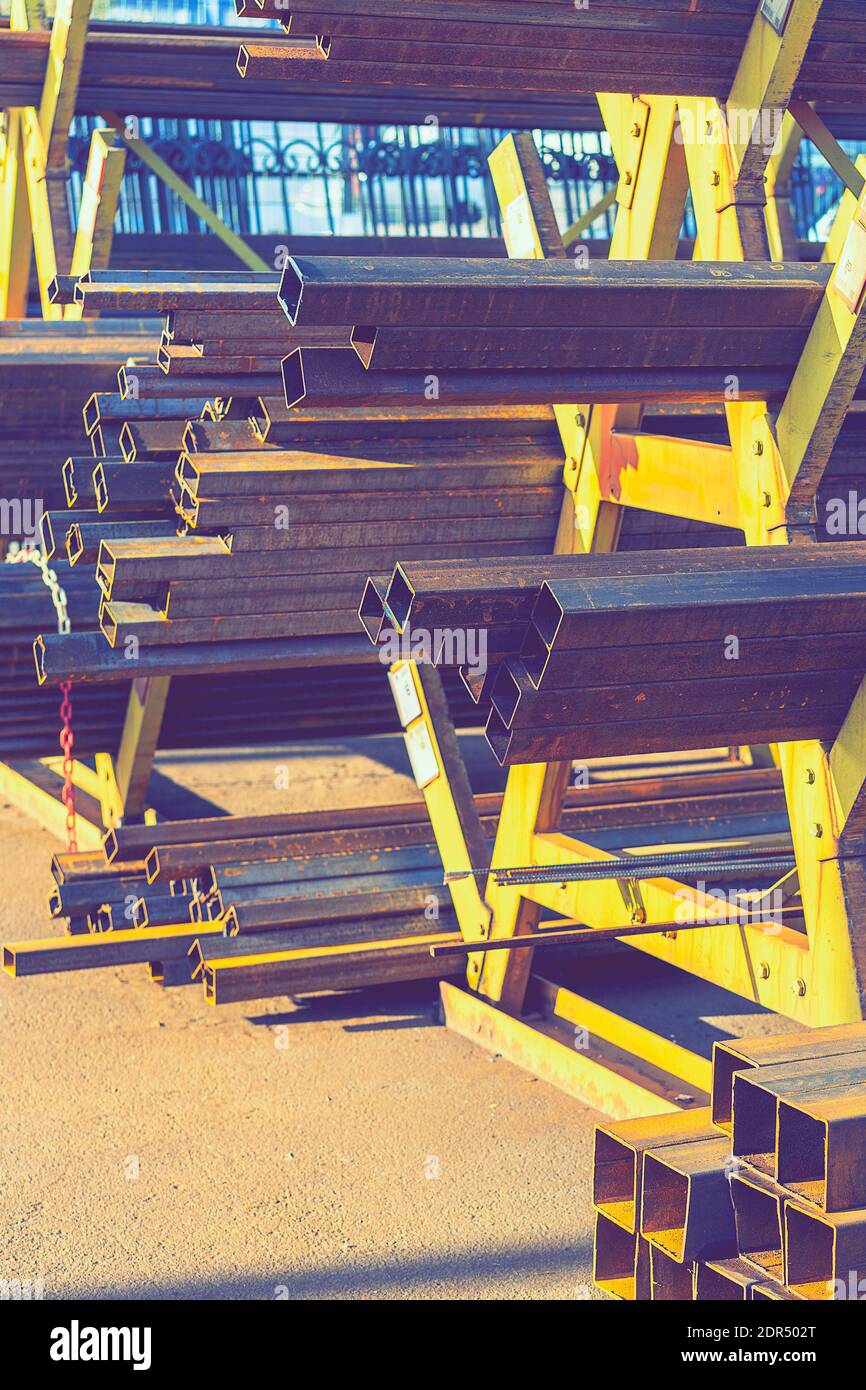 stack of steel pipe and metal beams on rack. metal pipes, profiles, rods, corners, rails, a choice of metal products. vertical photo. toned Stock Photo