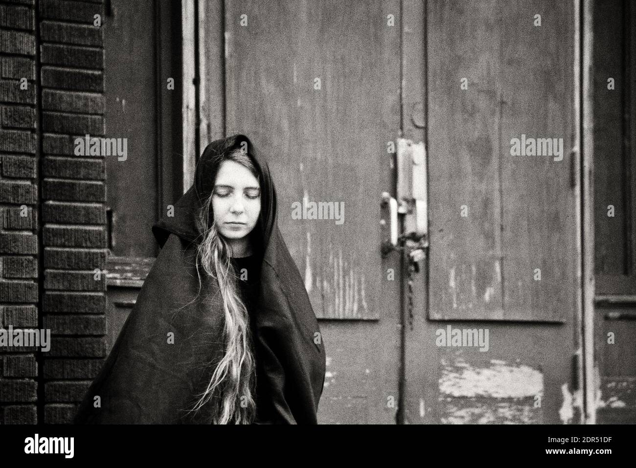 Young Woman Sitting In Front Of An Abandoned Factory Building Stock Photo