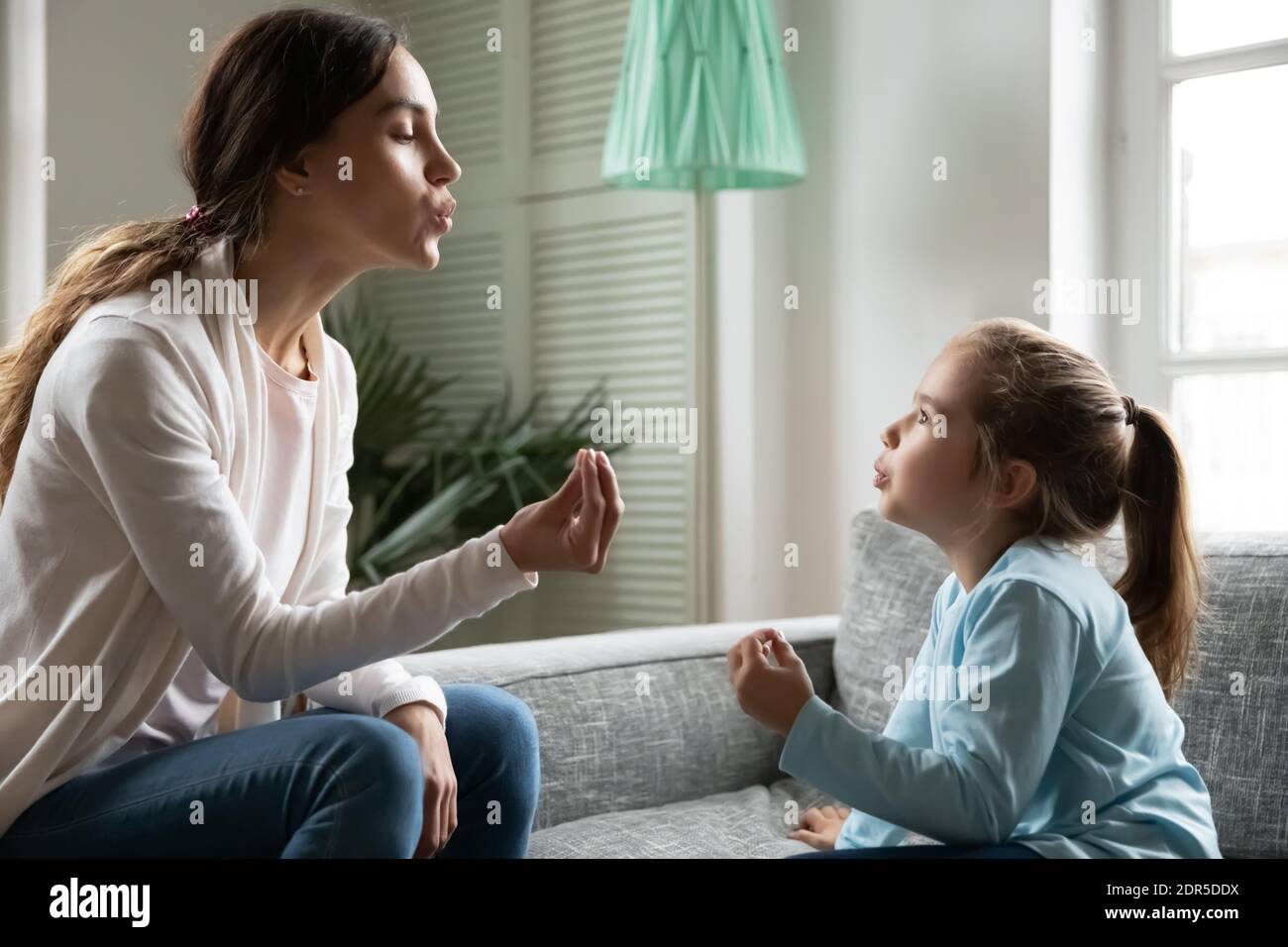 Close up little girl involved in lesson with speech therapist Stock Photo