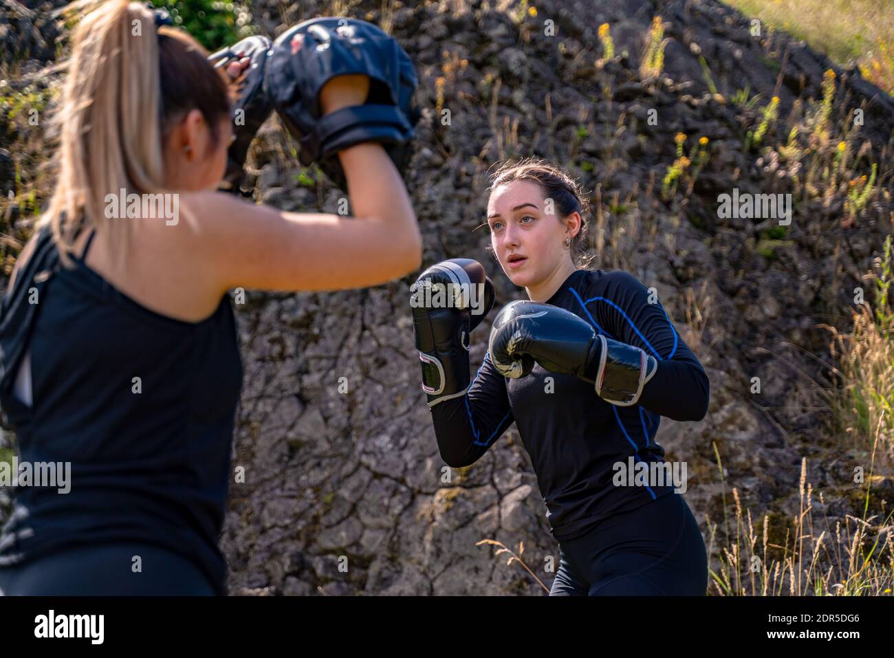 People training during a boxing class outdoor, using boxing mitts with a partner Stock Photo