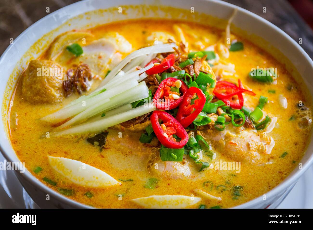 a bowl of laksa rice noodles in mild curry gravy with hard boiled egg