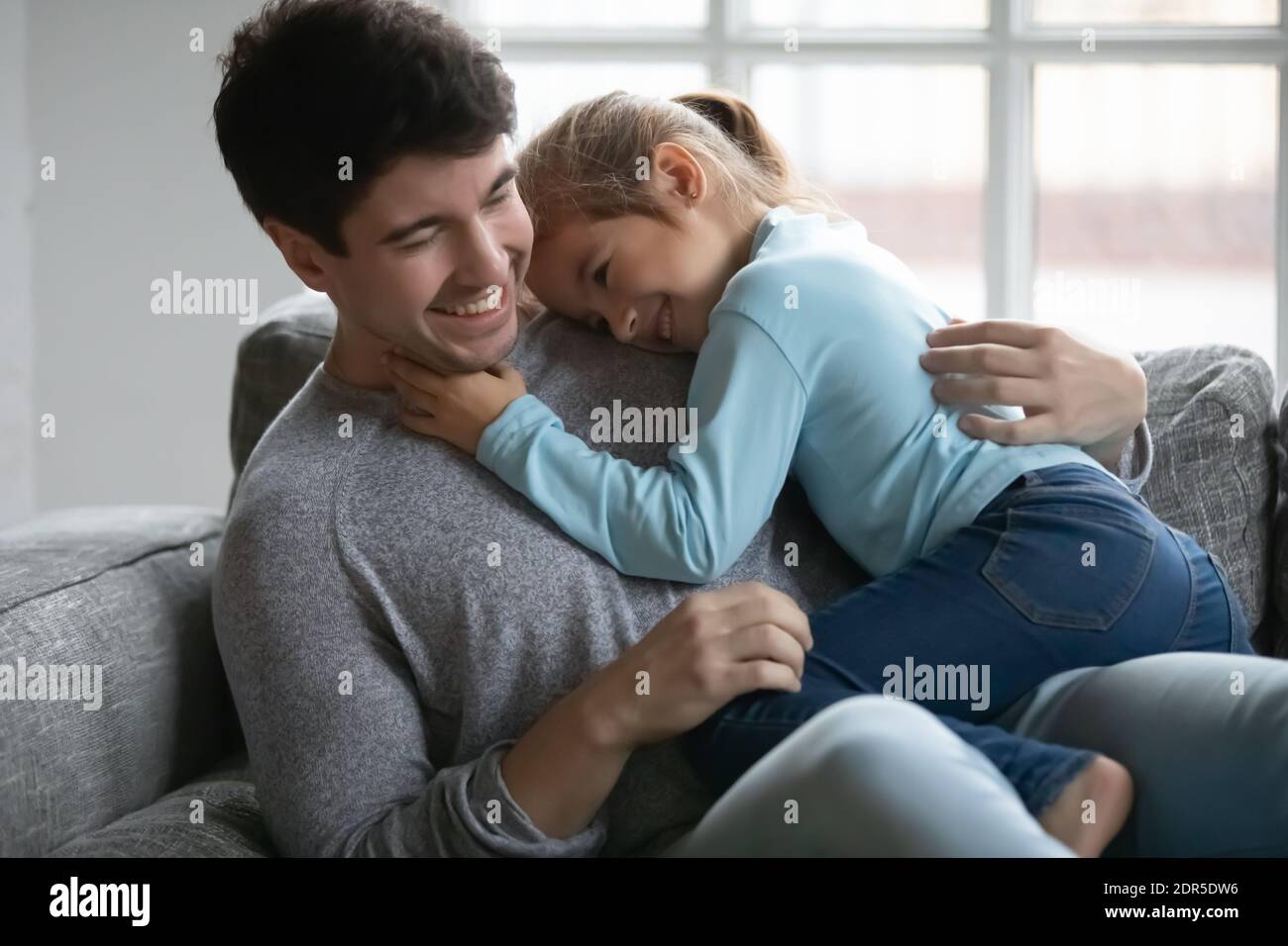 Close up happy father and little daughter cuddling on couch Stock Photo