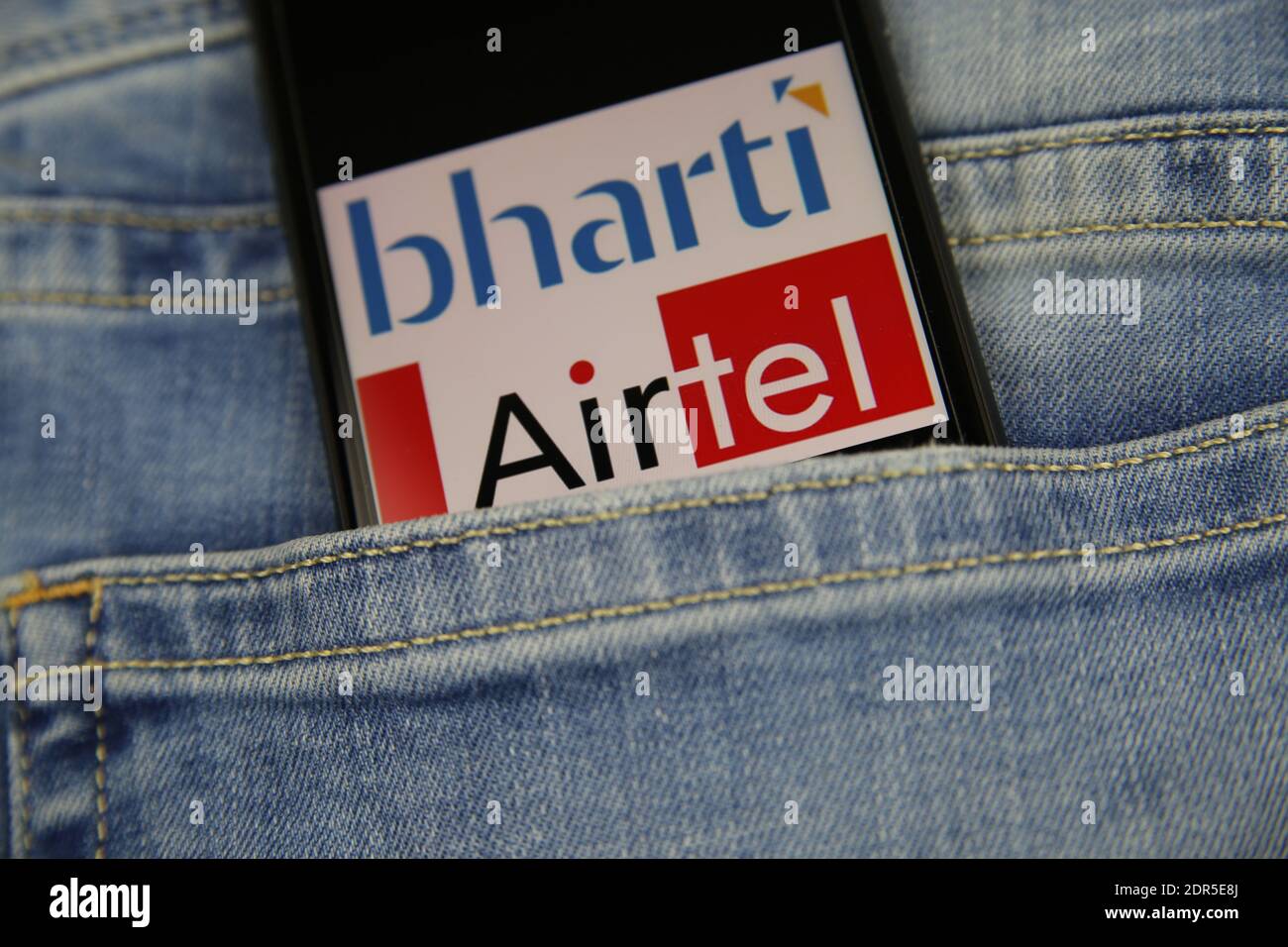 Viersen, Germany - May 9. 2020: Close up of smartphone screen in blue jeans pocket with logo lettering of indian mobile phone provider bharti Airtel ( Stock Photo