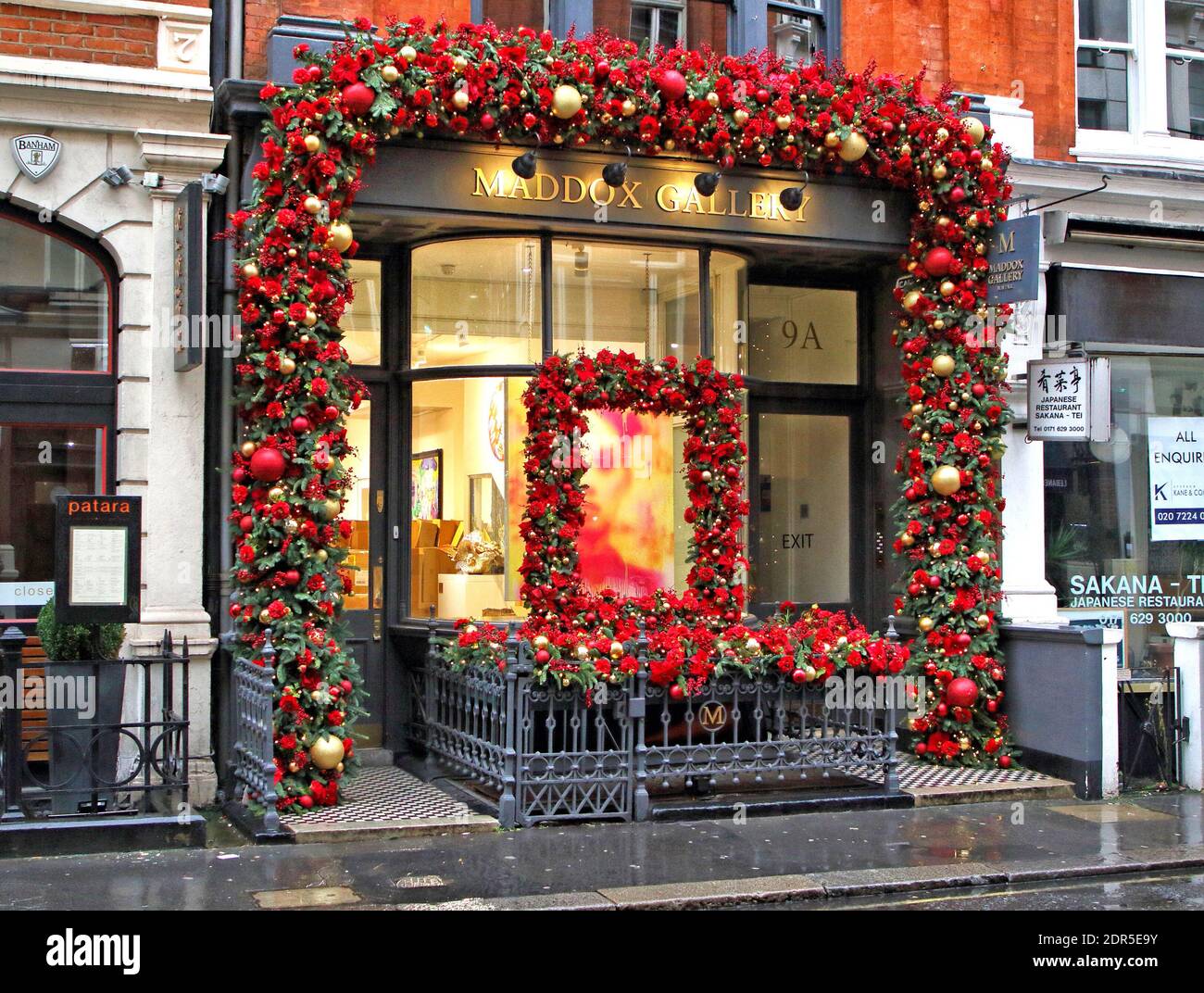 London, UK. 19th Dec, 2020. Colourful red flowers and baubles outside Maddox Gallery near Regent Street.Despite London being placed under extremely high Tier 4 restrictions to prevent the spread of Covid-19, with indoor venues, non essential retail and clubs all closed and inability to trade, there are many colourful Christmas displays around the city. Credit: SOPA Images Limited/Alamy Live News Stock Photo
