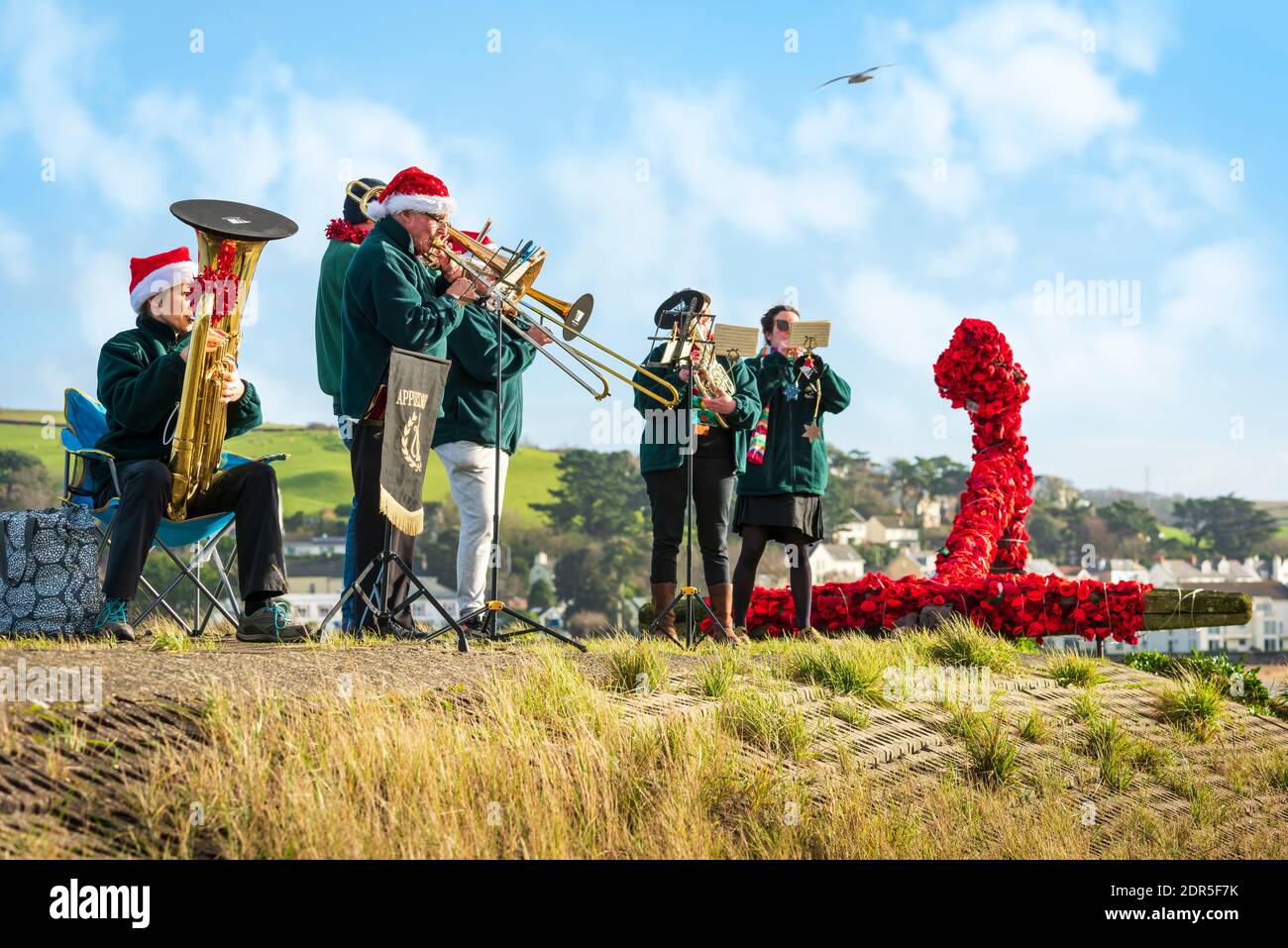 Appledore, North Devon, England. Sunday 20th December 2020. UK Weather. On a day of sunshine and heavy showers on the North Devon coast, the Appledore Band performs on the quayside by playing 'Socially Distanced' carols for the local community who dare to venture out between the downpours. Credit: Terry Mathews/Alamy Live News Stock Photo