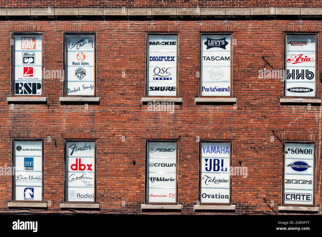 Multiple brand names covering the windows of an old building in Montreal, Canada Stock Photo
