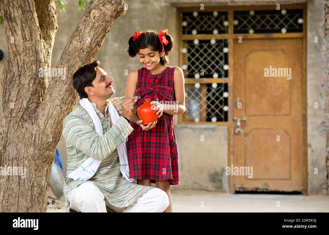 Rural Indian father with daughter holding piggy bank Stock Photo - Alamy