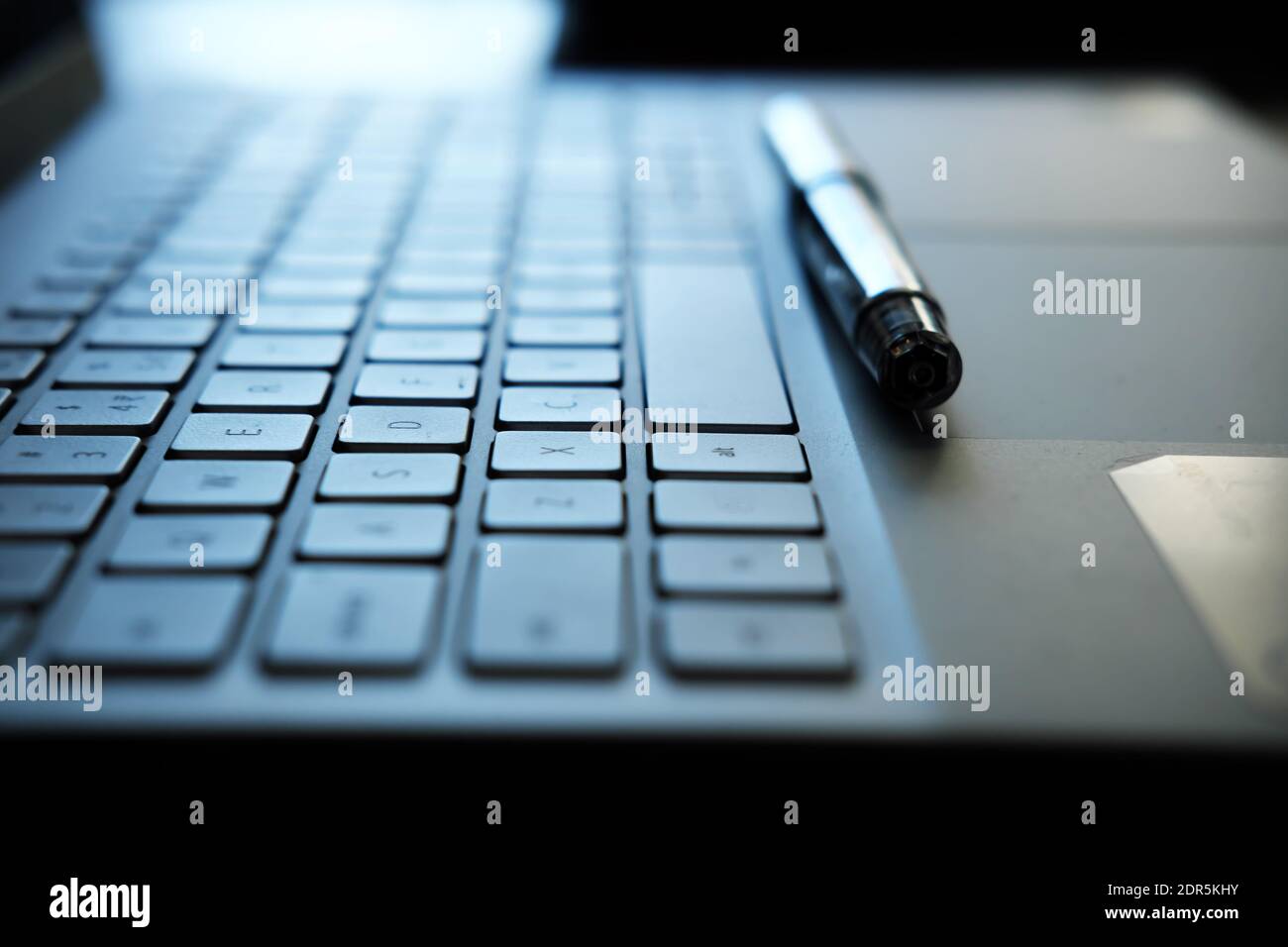 laptop keyboard and pen - photo representing remote work concept with selective focus Stock Photo