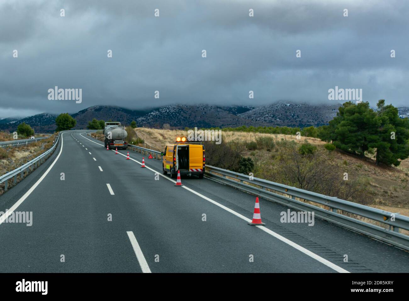 Road maintenance vehicle signaling a damaged tanker on the highway. Stock Photo