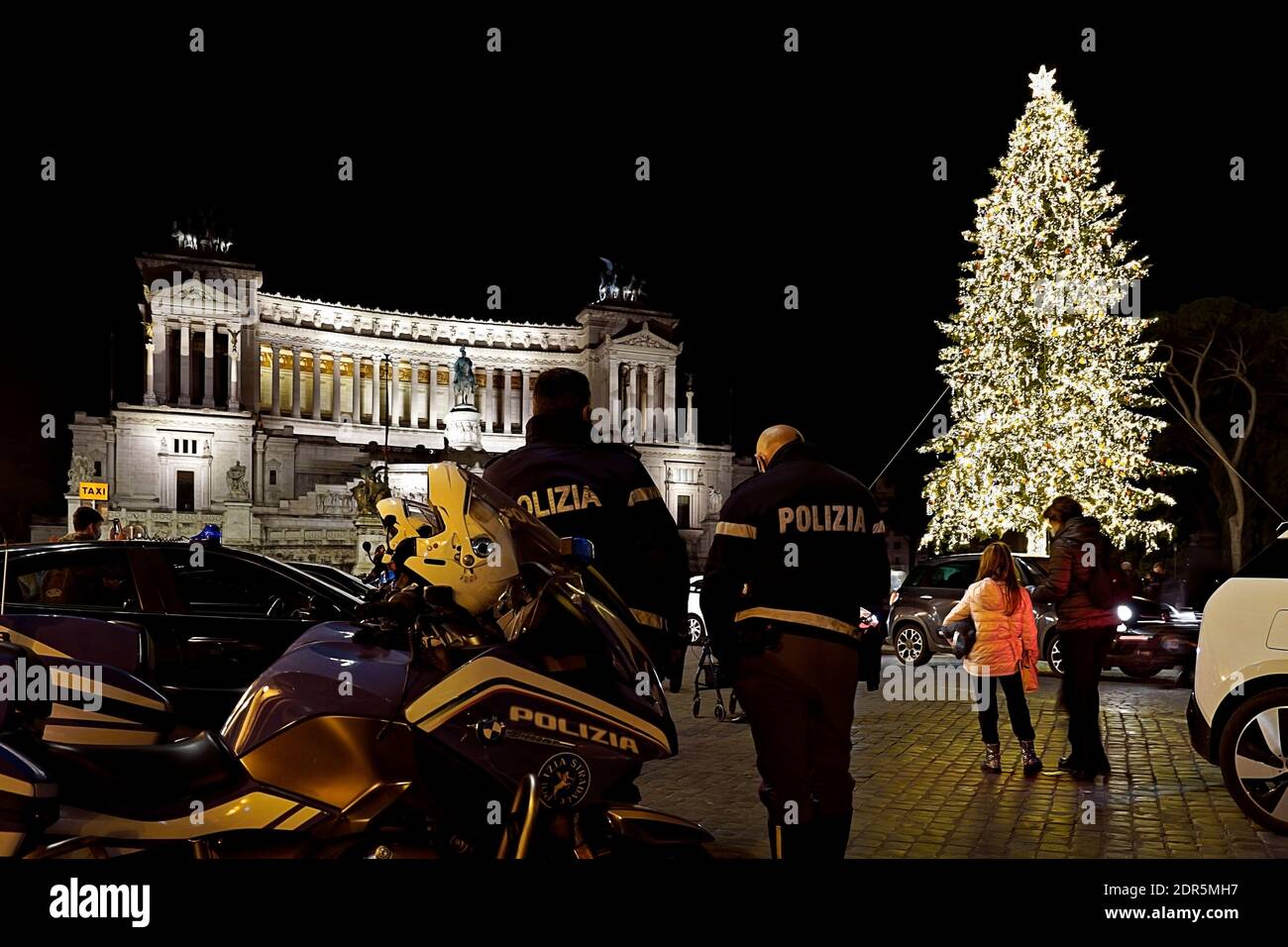 Police officers patrol Venice Square during Christmas holidays. Led lights traditional huge tree set up in Piazza Venezia. Rome, Italy, Europe, EU. Stock Photo