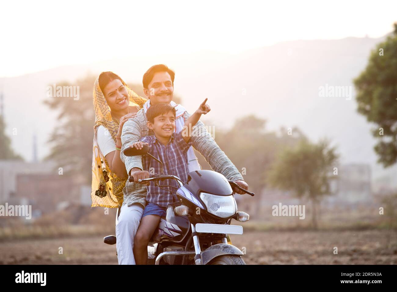 Happy rural Indian family riding on motorcycle Stock Photo