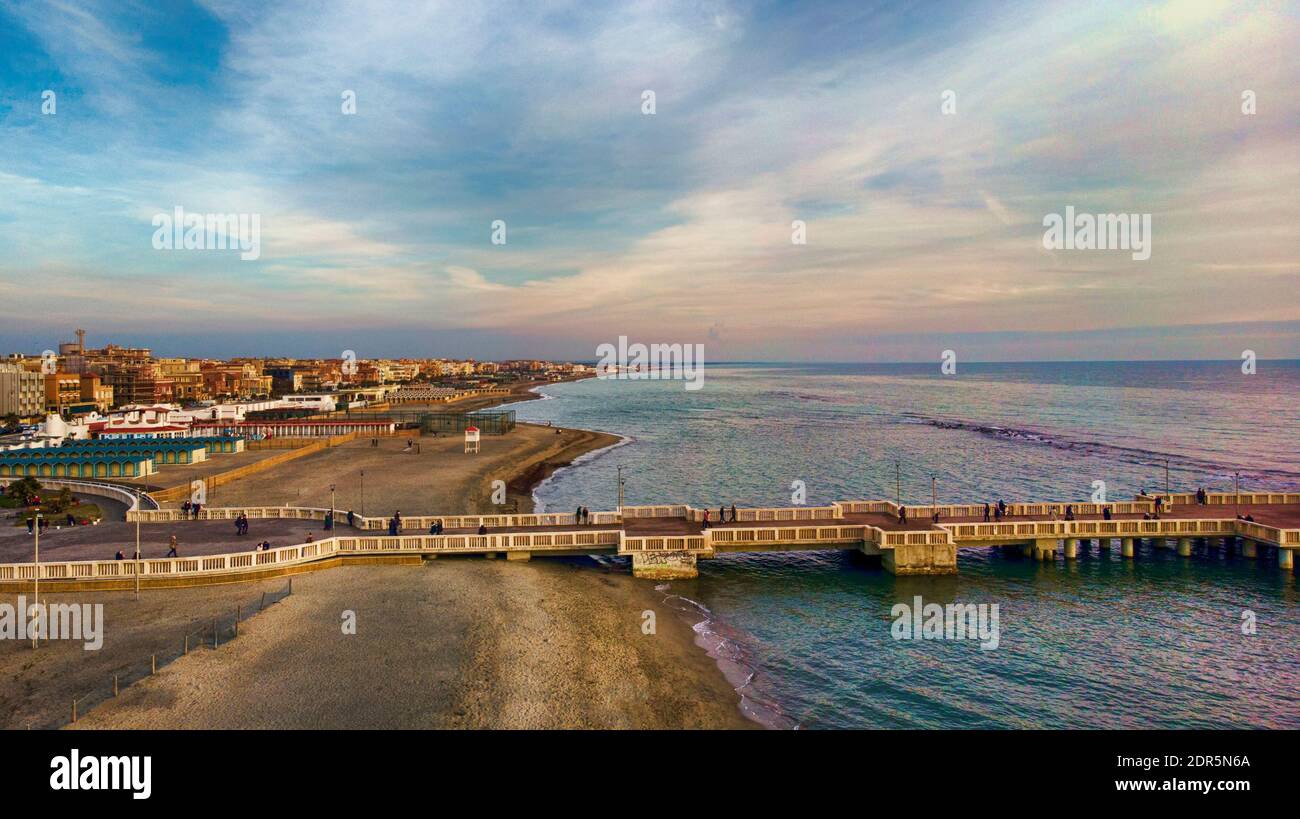 Sunset Rome aerial view in Ostia Lido beach over blue sea and brown sandy beach, beautiful coast line with glimpse of pedestrian pier a landmark of to Stock Photo