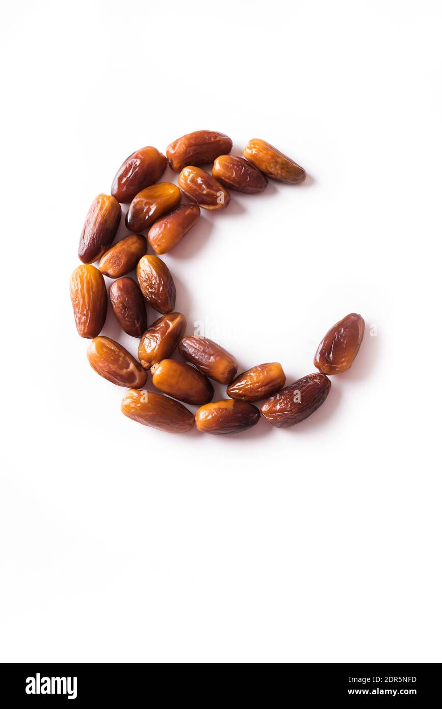 Islamic Crescent. Ramadan kareem with dates fruits arranged in shape of crescent moon isolated on white background, top view, copy space. Iftar food c Stock Photo