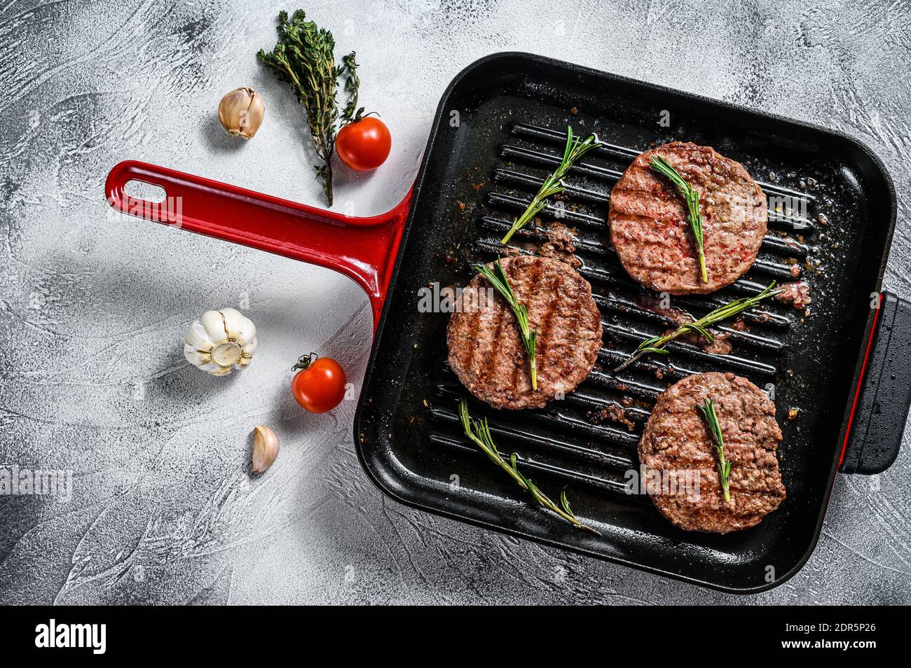 Beef burger patties sizzling on a hot barbecue pan. White background