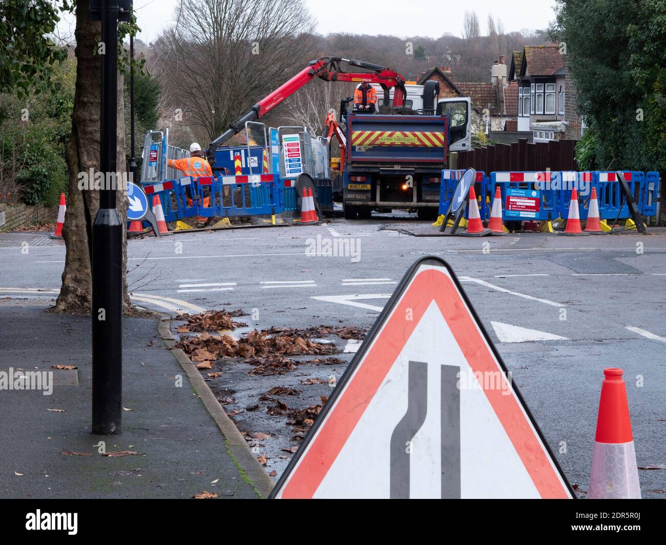 Thames Water dig holes in the road to lay pipes with truck mounted excavator Stock Photo