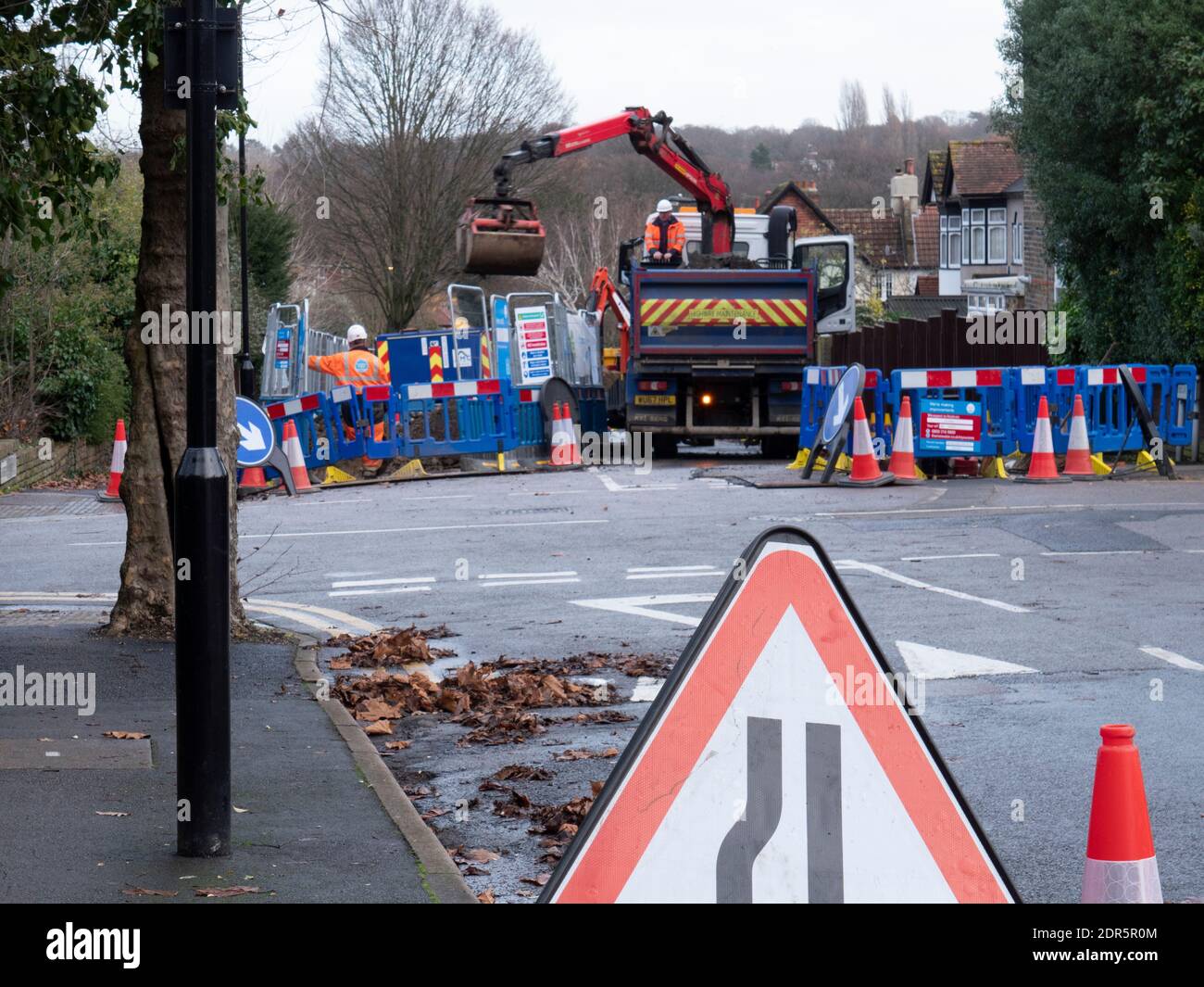 Thames Water dig holes in the road to lay pipes with truck mounted excavator Stock Photo