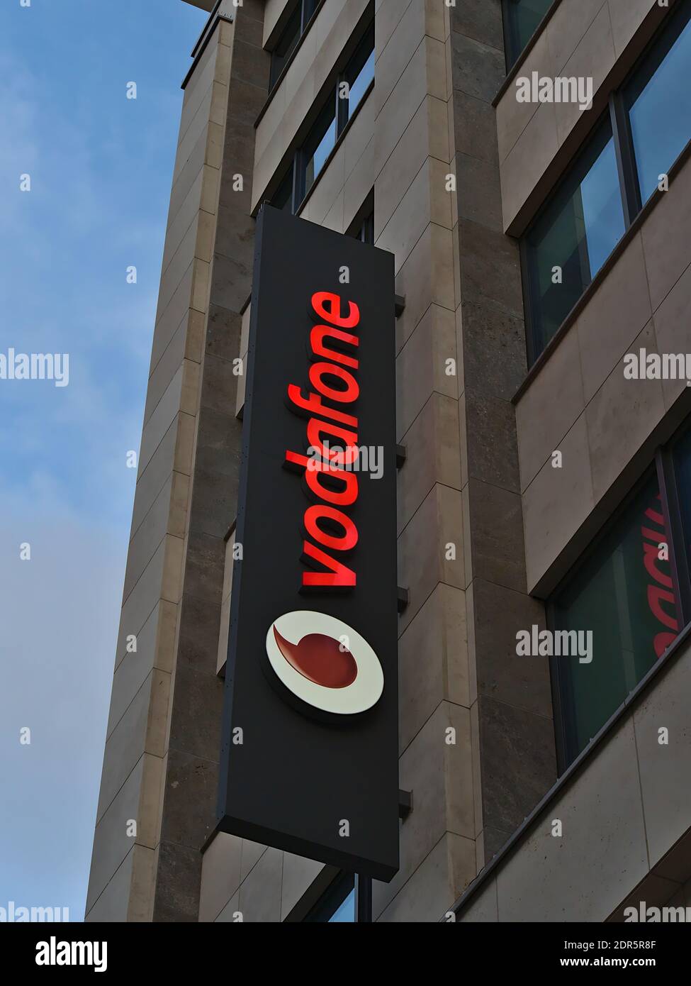 Big Vodafone (telecommunications business) advertising sign with company logo on building facade above branch in shopping street Königstraße. Stock Photo