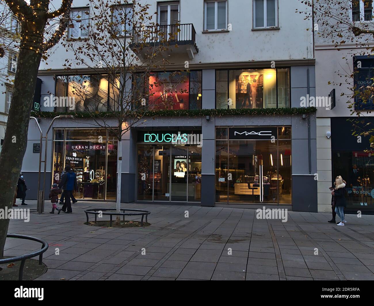 People passing by the closed branch of German perfumery retail chain Douglas in shopping street Königstraße during Covid-19 lockdown. Stock Photo
