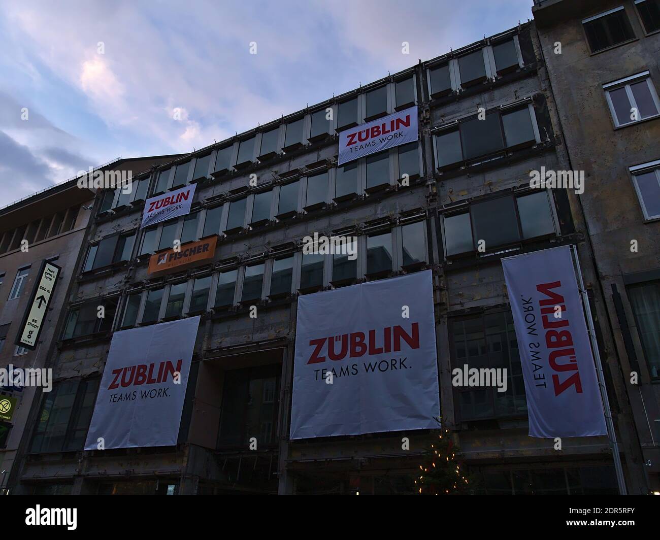 Construction site in shopping street Königstraße in downtown with banners of construction company Züblin, part of Strabag Group, in evening light. Stock Photo